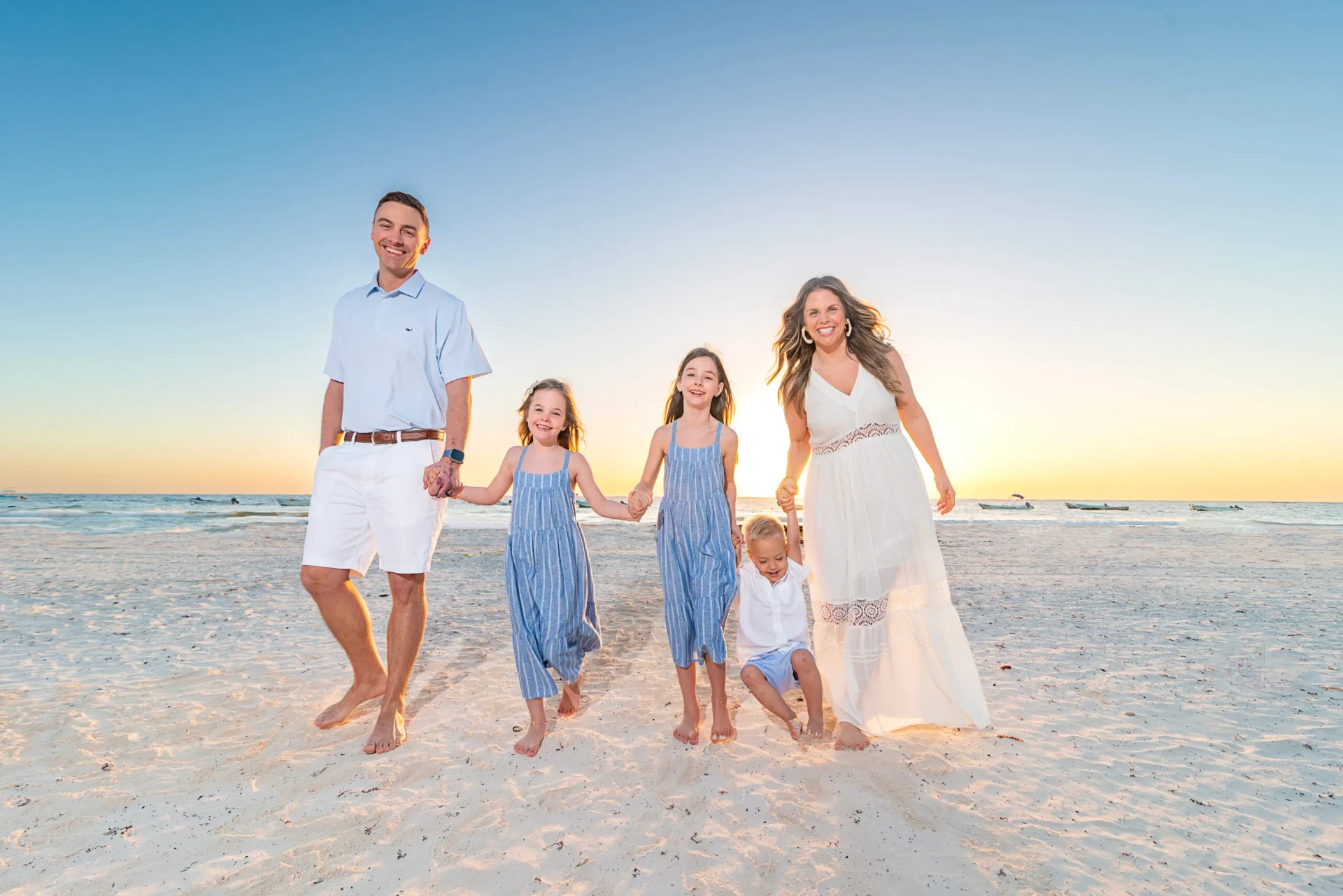 Family of five holding hands on a white-sand beach at sunset during a Riviera Maya family photography session