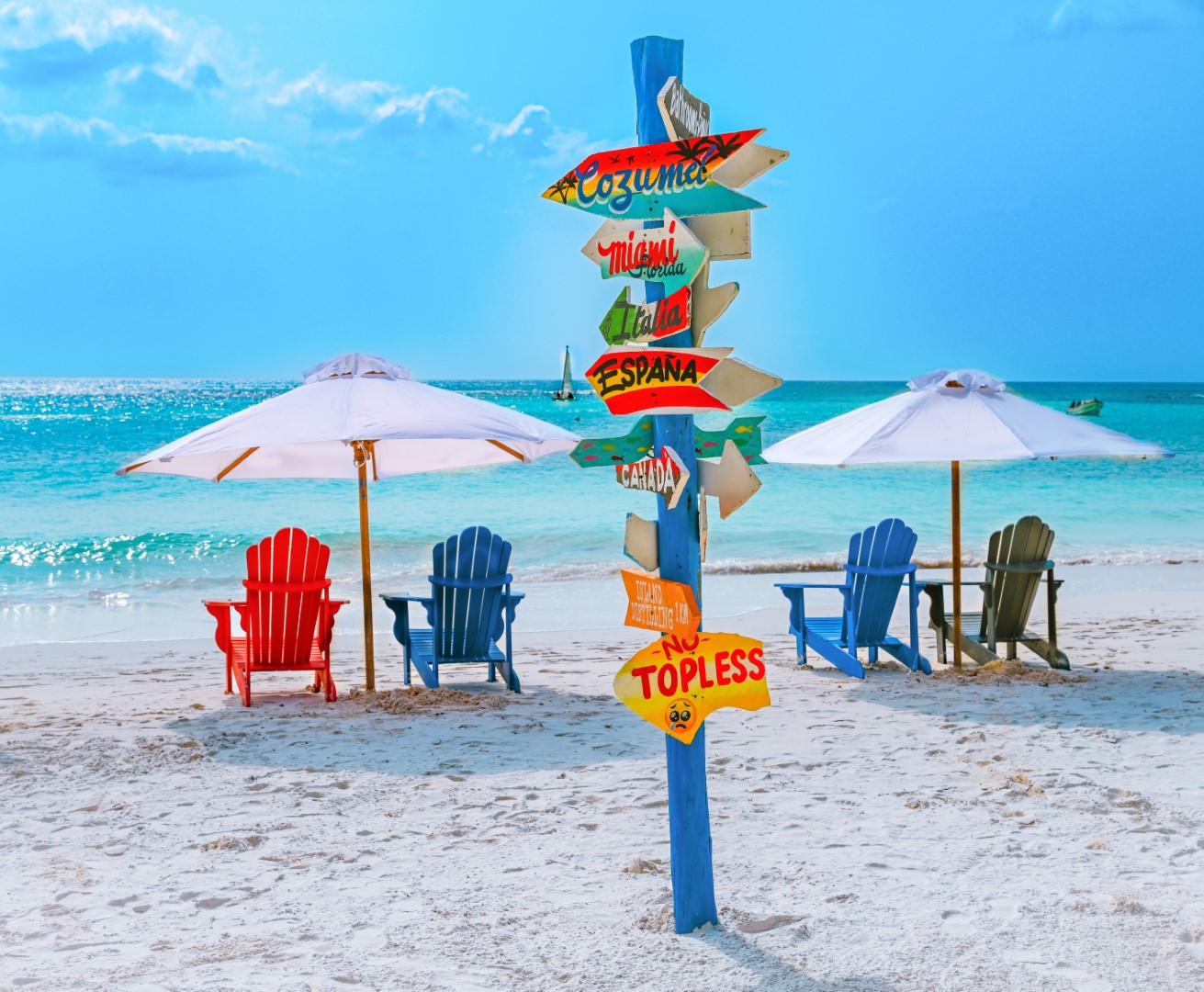 Colorful beach chairs, umbrellas and a destination signpost on the white sand at La Playa Xpu-Ha Beach Club
