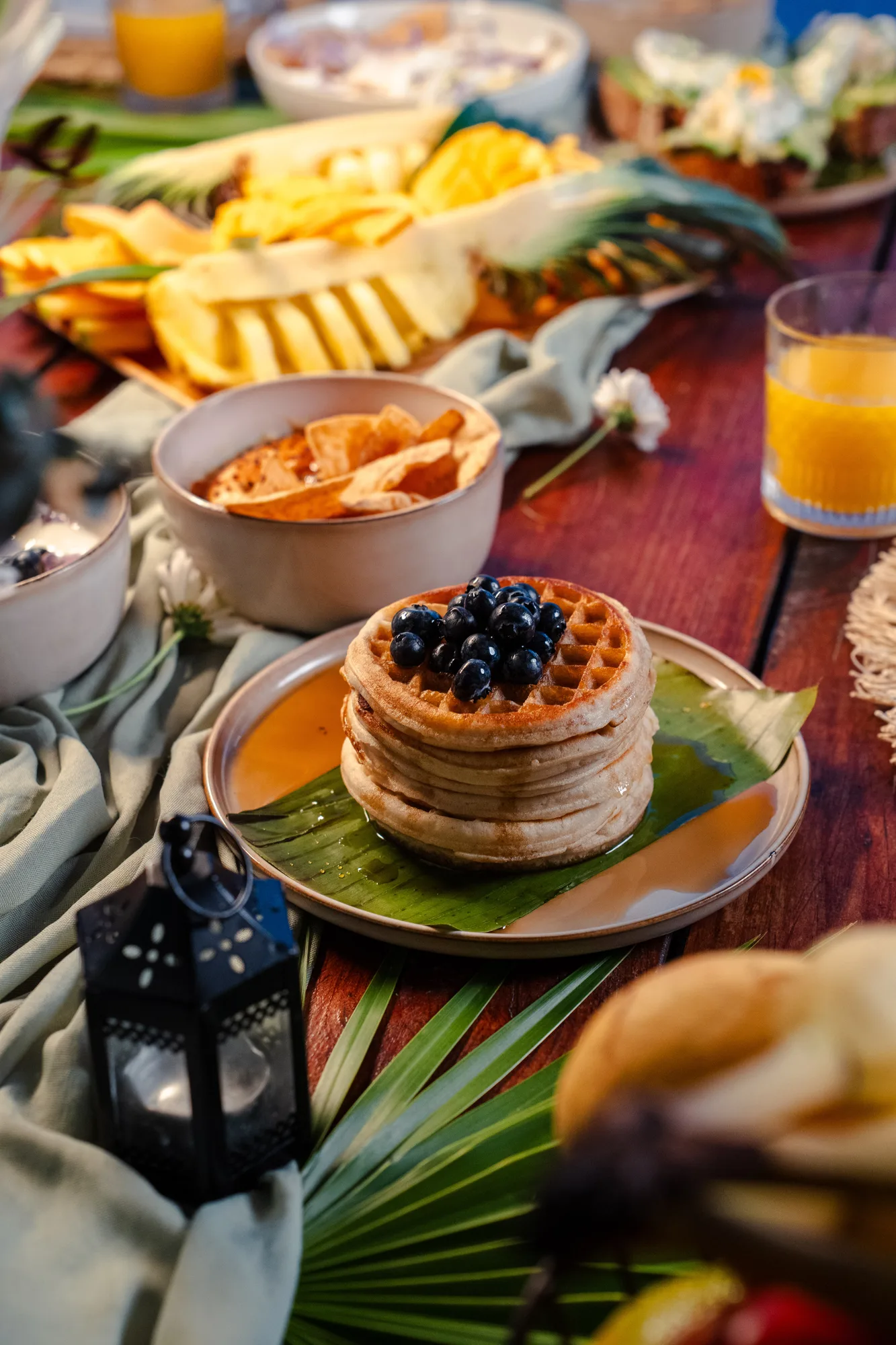 Waffles con arándanos frescos en una mesa de desayuno tropical