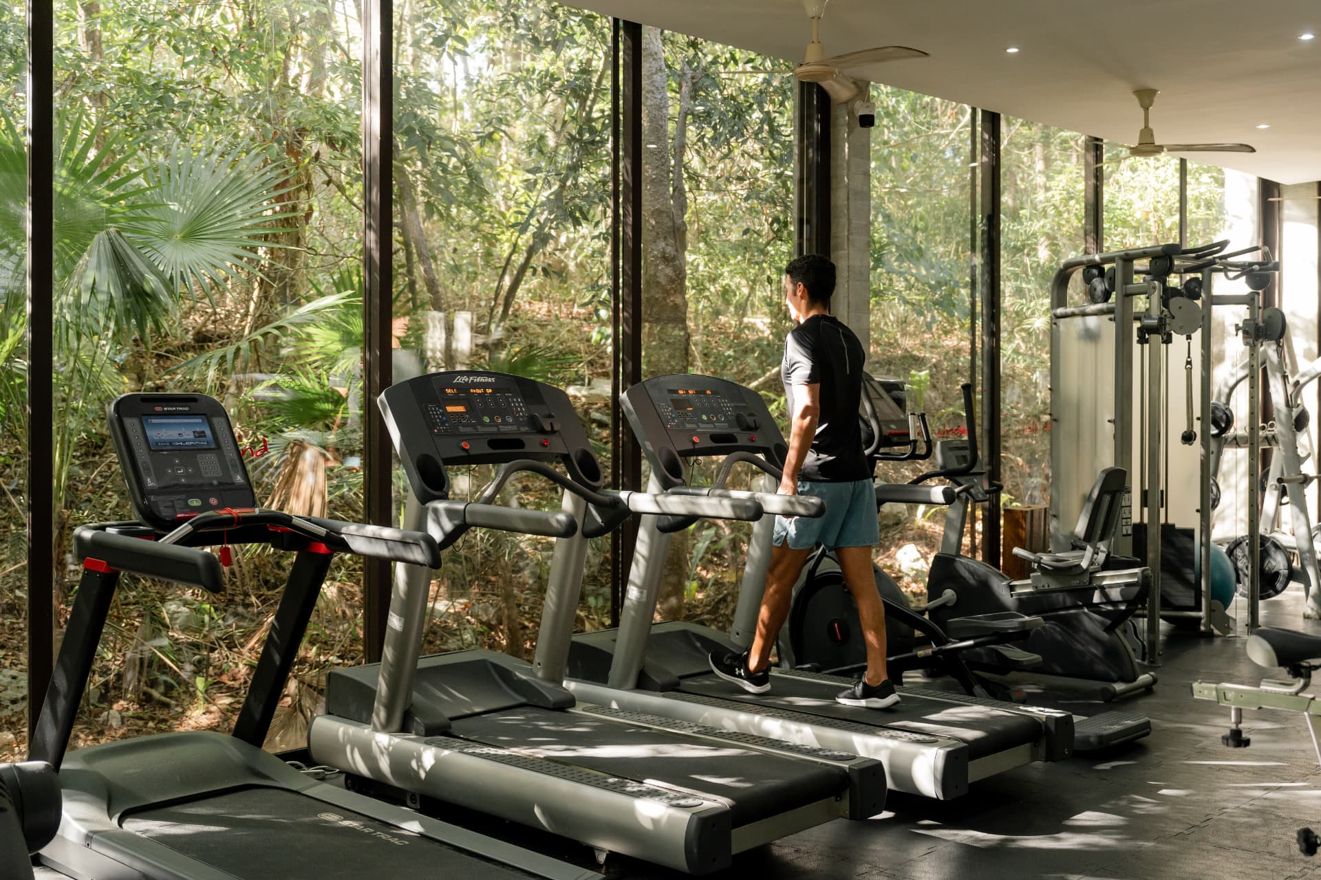 Glass-walled wellness center gym surrounded by jungle at Tulum Country Club
