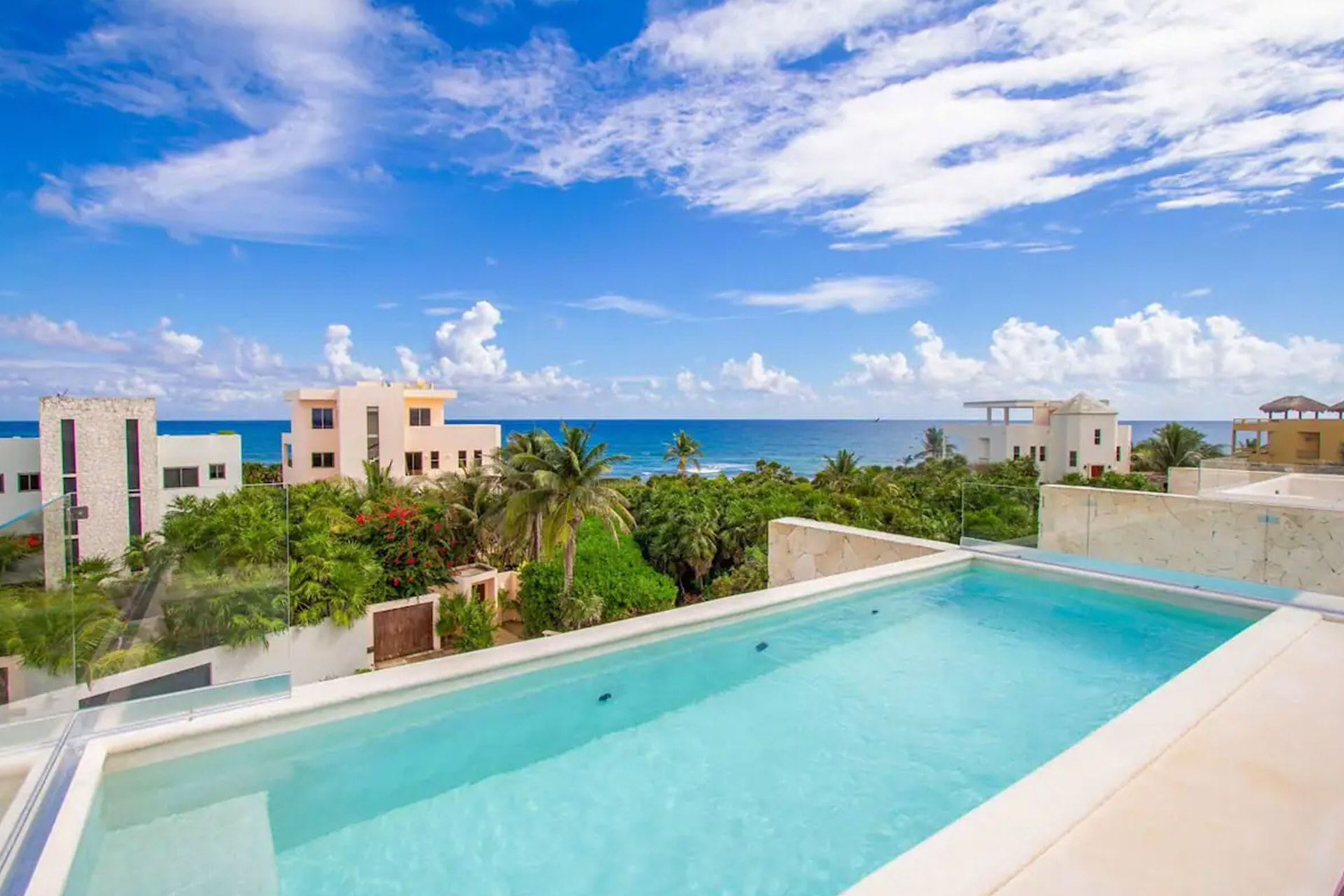 Rooftop pool terrace with turquoise water overlooking the Caribbean Sea and Riviera Maya coastline