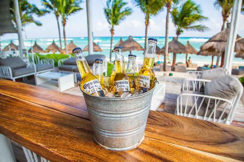 Beach club bar in Akumal with a bucket of cold Coronitas, turquoise ocean and palapa umbrellas in the background