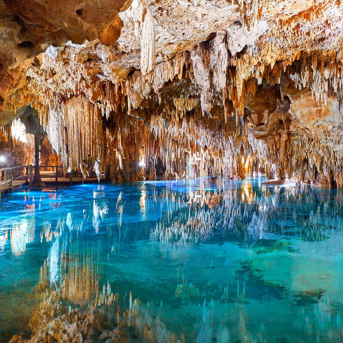 Crystal-clear turquoise water inside Aktun Chen cenote cave with dramatic stalactites near Akumal