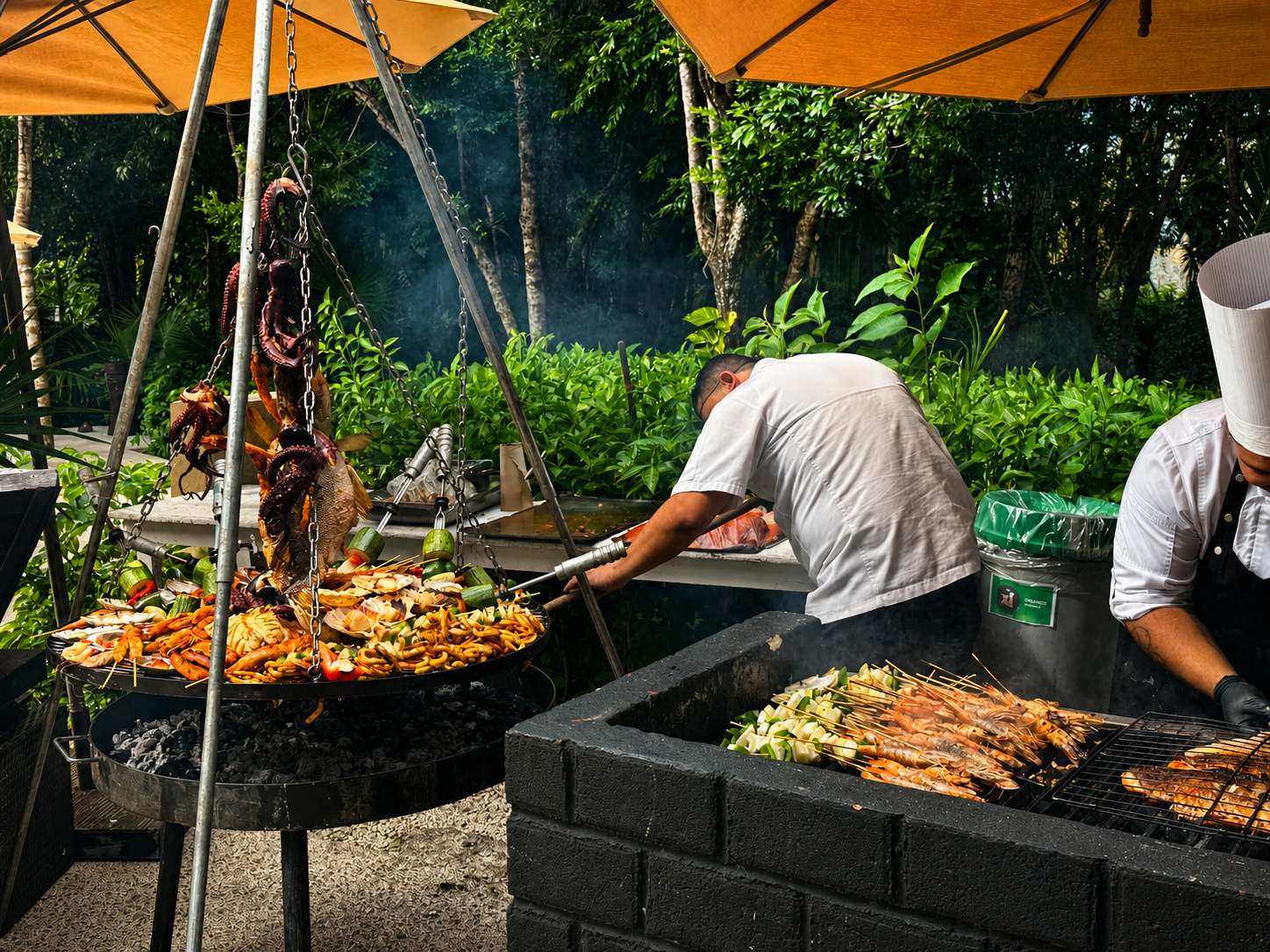 Outdoor grill station at El Cenote Snack Bar with chefs preparing seafood and meats under orange umbrellas inside Tulum Country Club