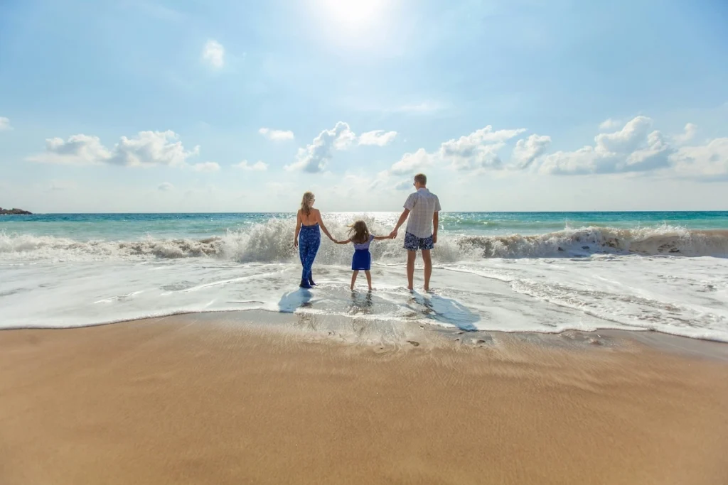Family holding hands at the shoreline on a sunny Akumal beach in the Riviera Maya
