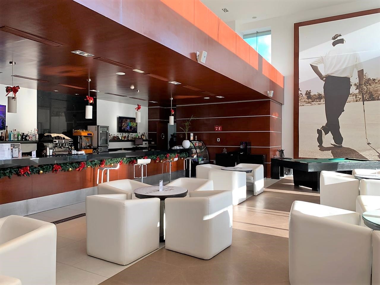 Mulligan's interior with white lounge seating, wooden bar counter, and golf-themed wall art